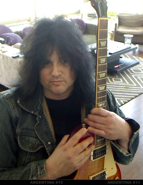 Benny Doro today, holding a guitar and looking back across the archive