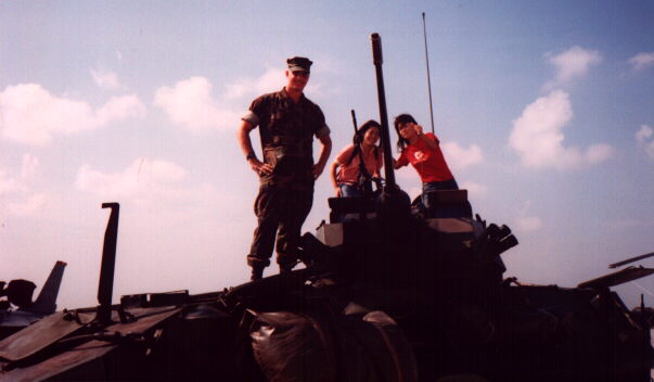 Three people on an armored vehicle.