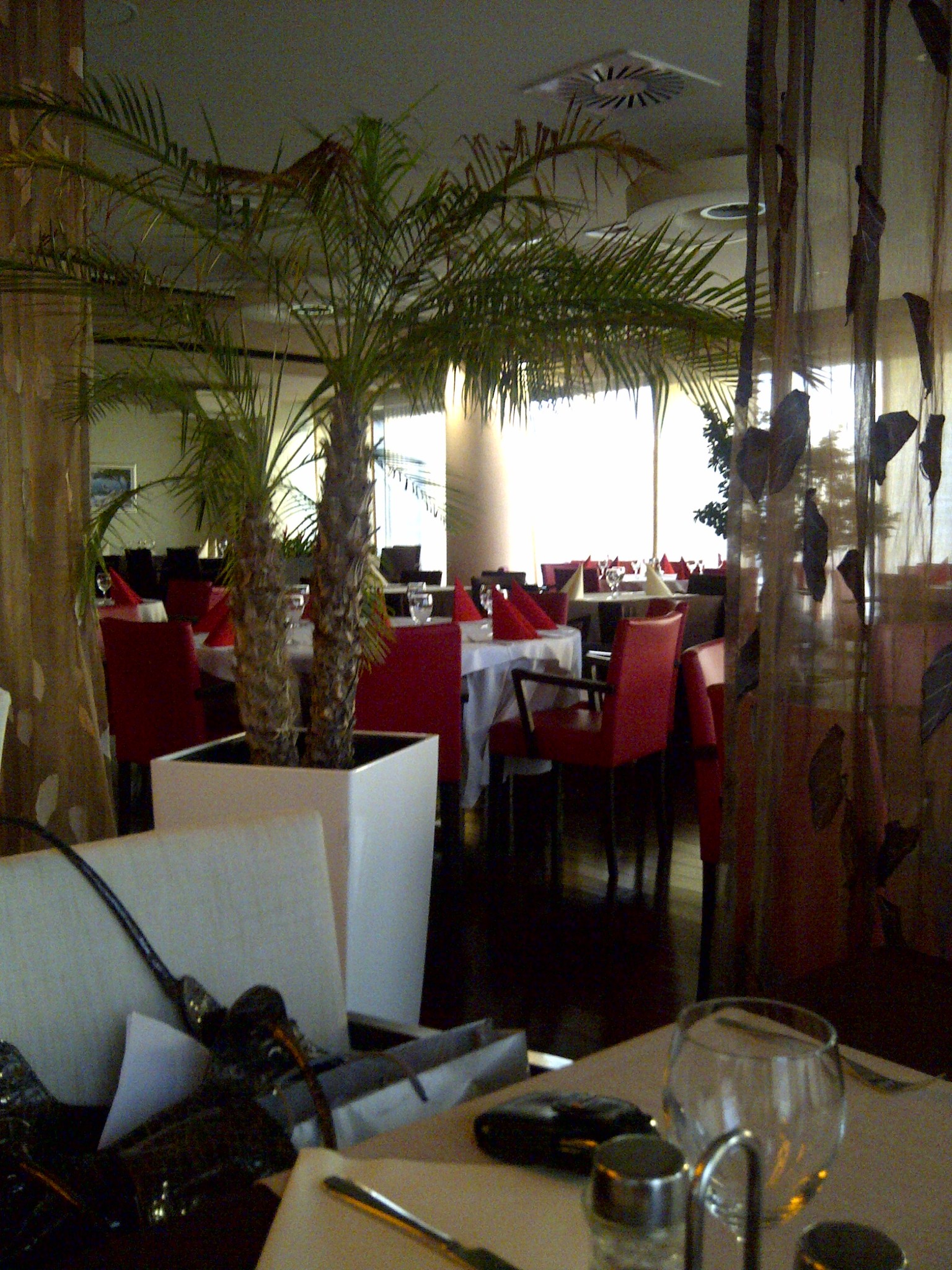 A restaurant dining room with red chairs and white tablecloths