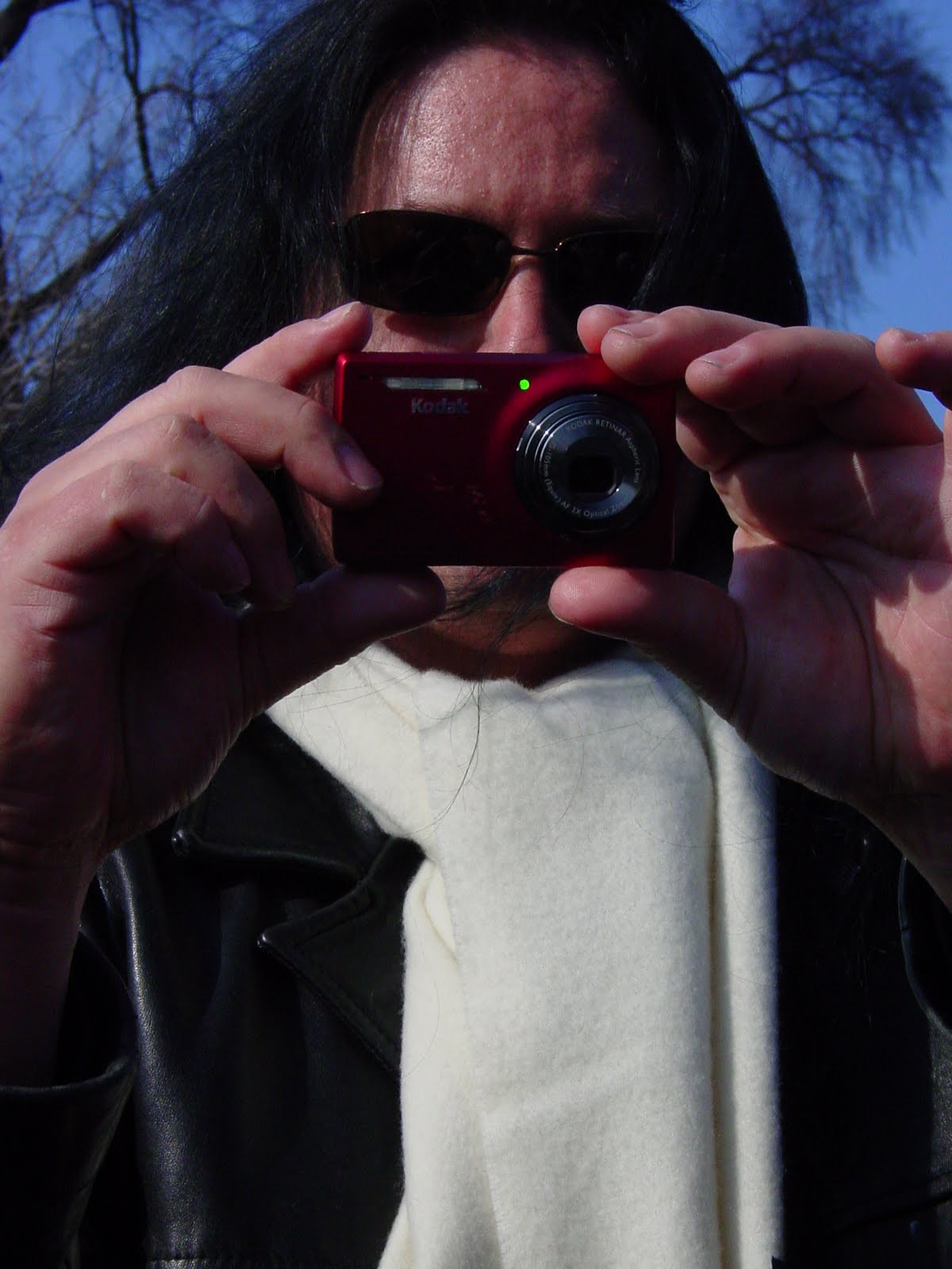 Benny in winter clothing holding a red Kodak camera up to take a photograph