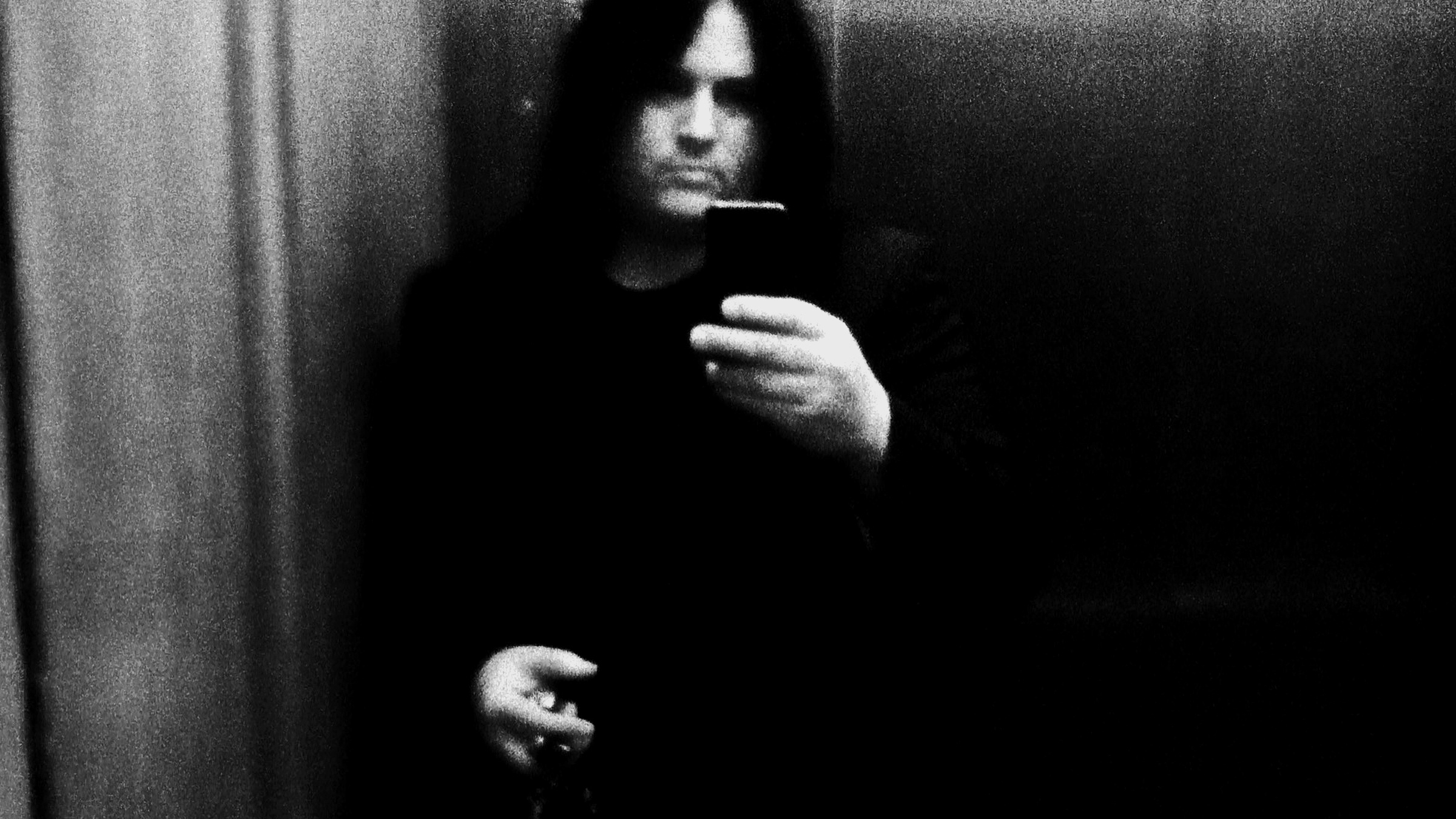 A grainy black-and-white mirror self-portrait of Benny Doro holding the camera