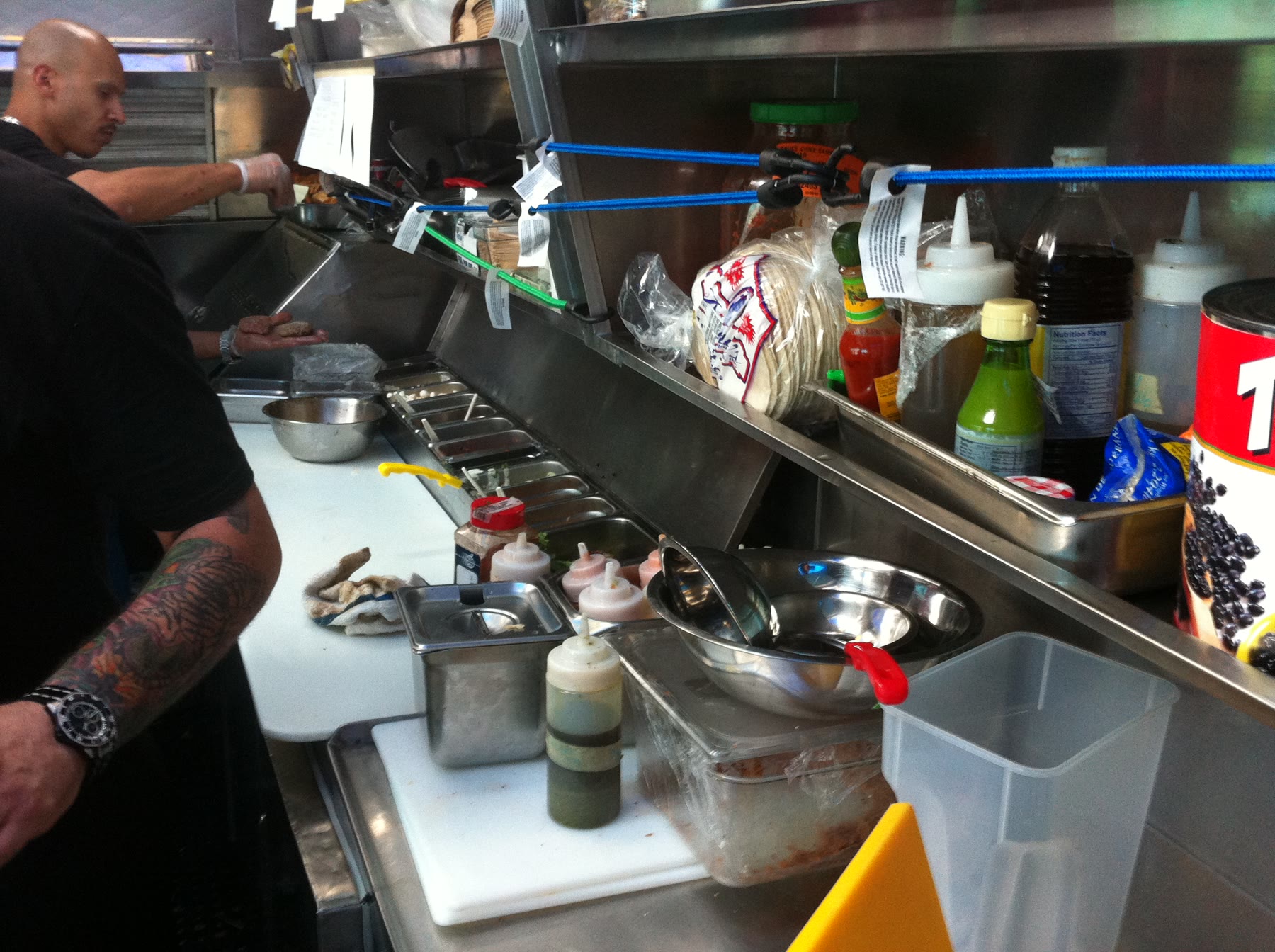Workers preparing food inside the narrow stainless-steel truck kitchen.
