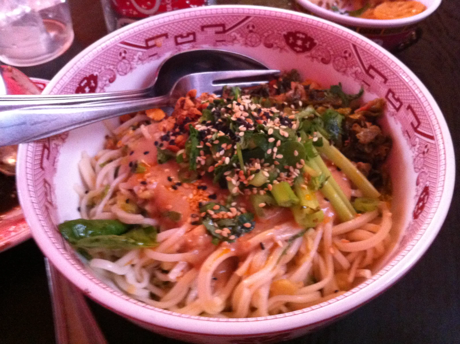 Close view of noodles, greens, and sesame