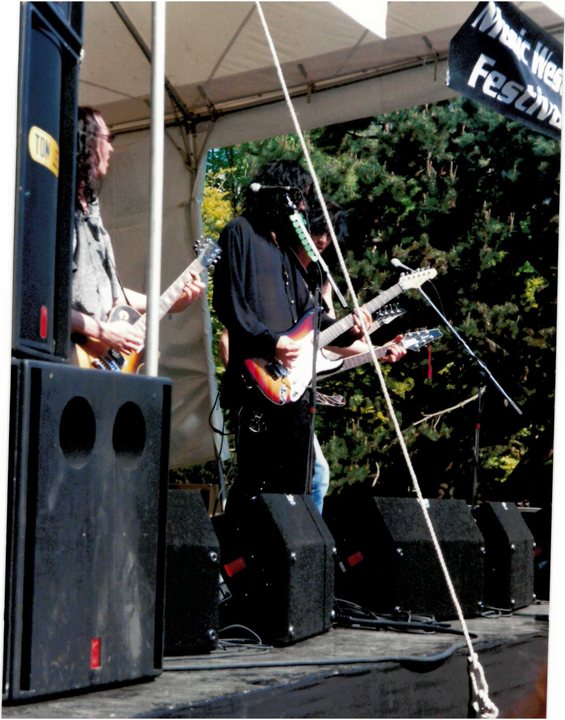 Guitarist performing beside a stage speaker stack