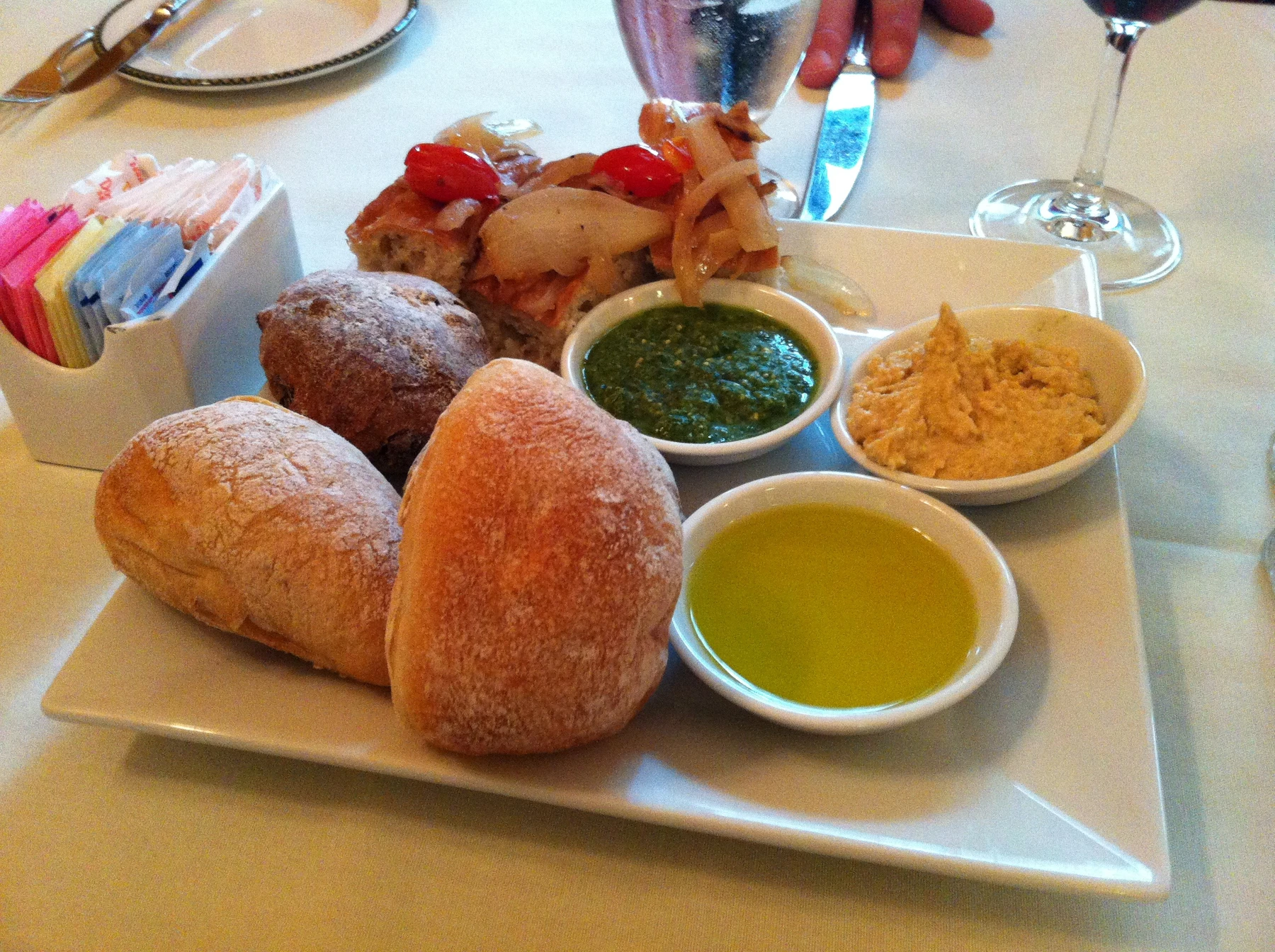 An abundant plate of rolls, focaccia, olive oil and dips right at the edge of the table