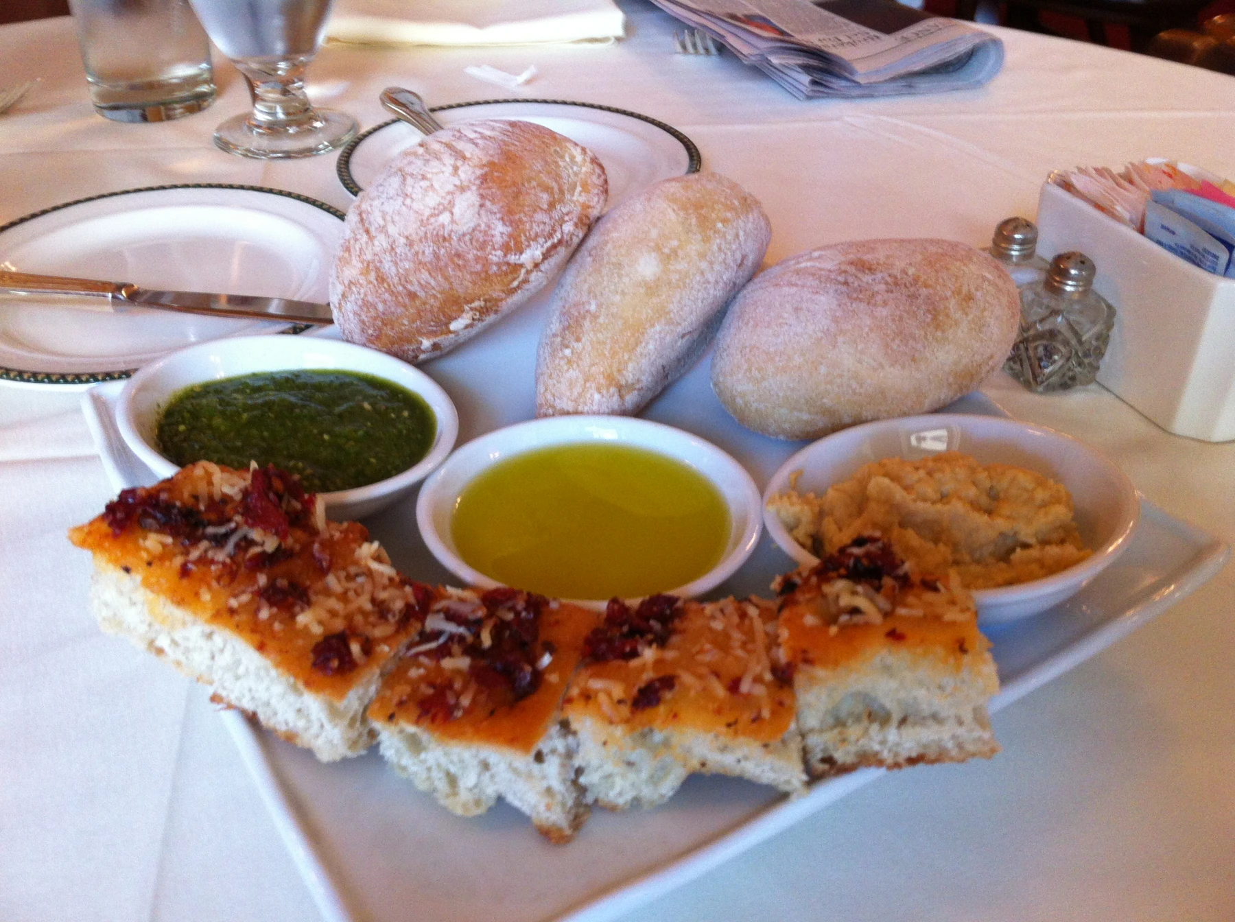 A plate of focaccia and rolls with three dipping sauces at 1792