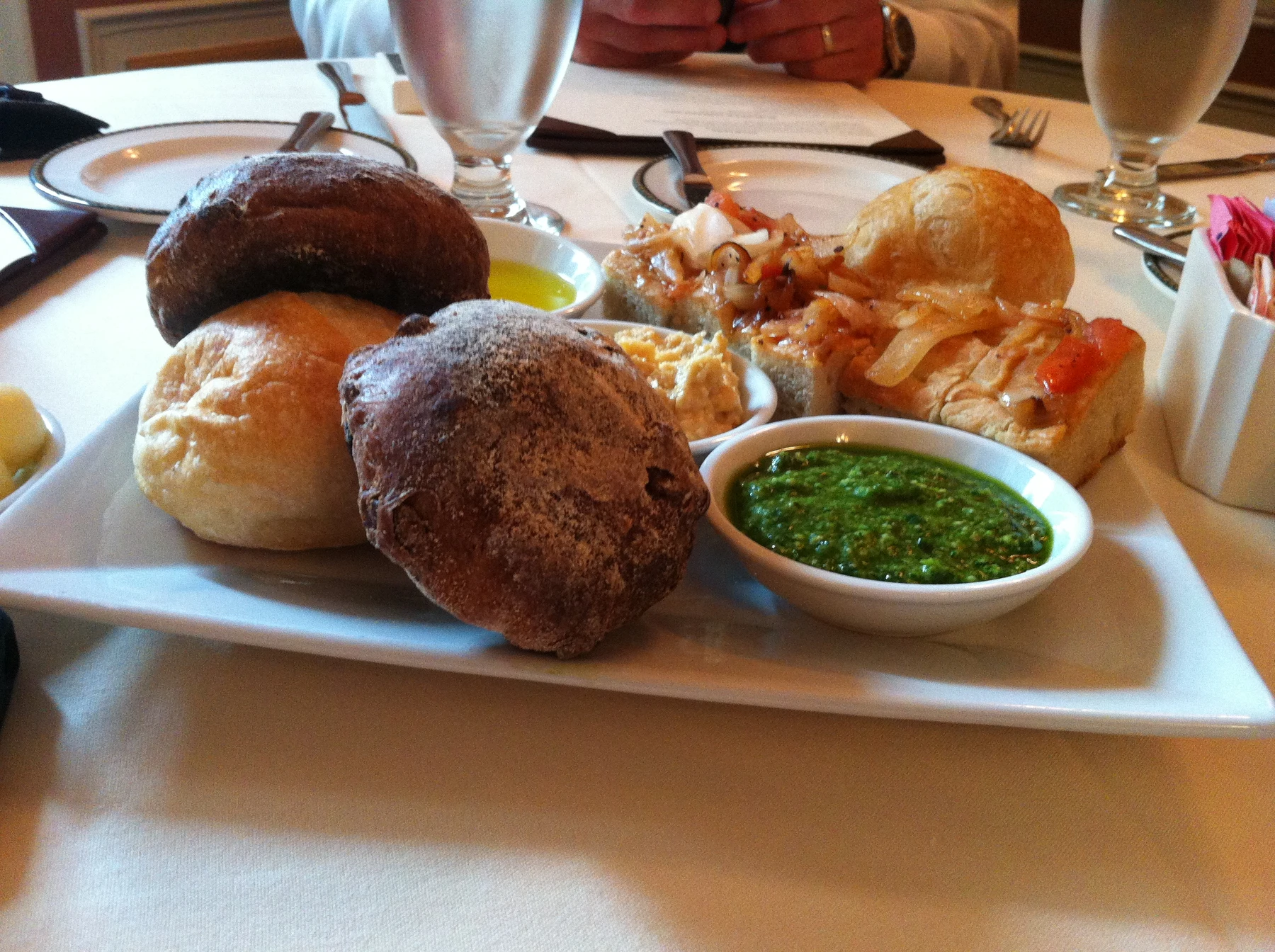 Sharp flour-dusted dark rolls, golden bread, vivid pesto and onion-topped focaccia filling the table